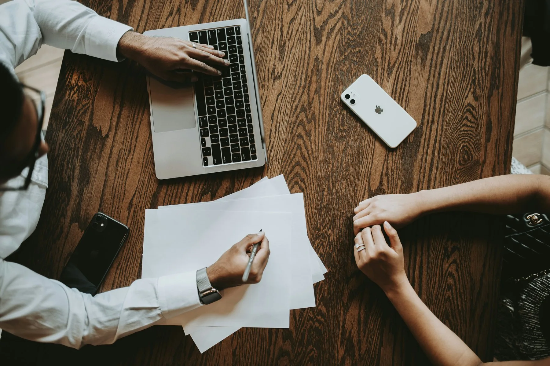 An agent drafting an offer across the table from their clients